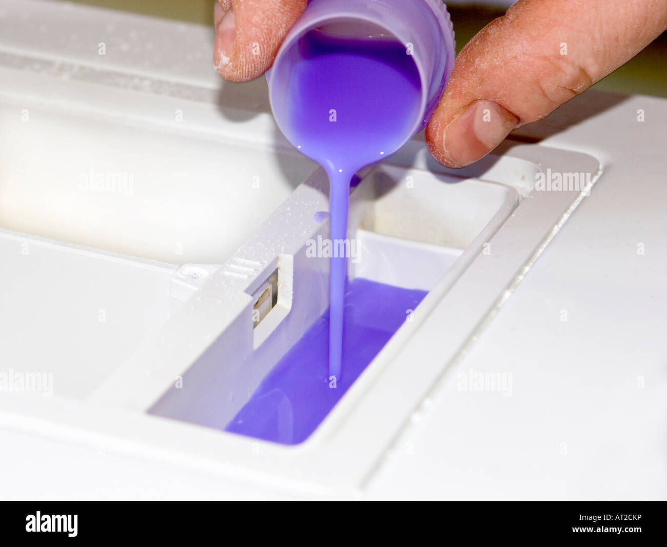 Man Pouring Fabric Softener into a Washing Machine Stock Photo