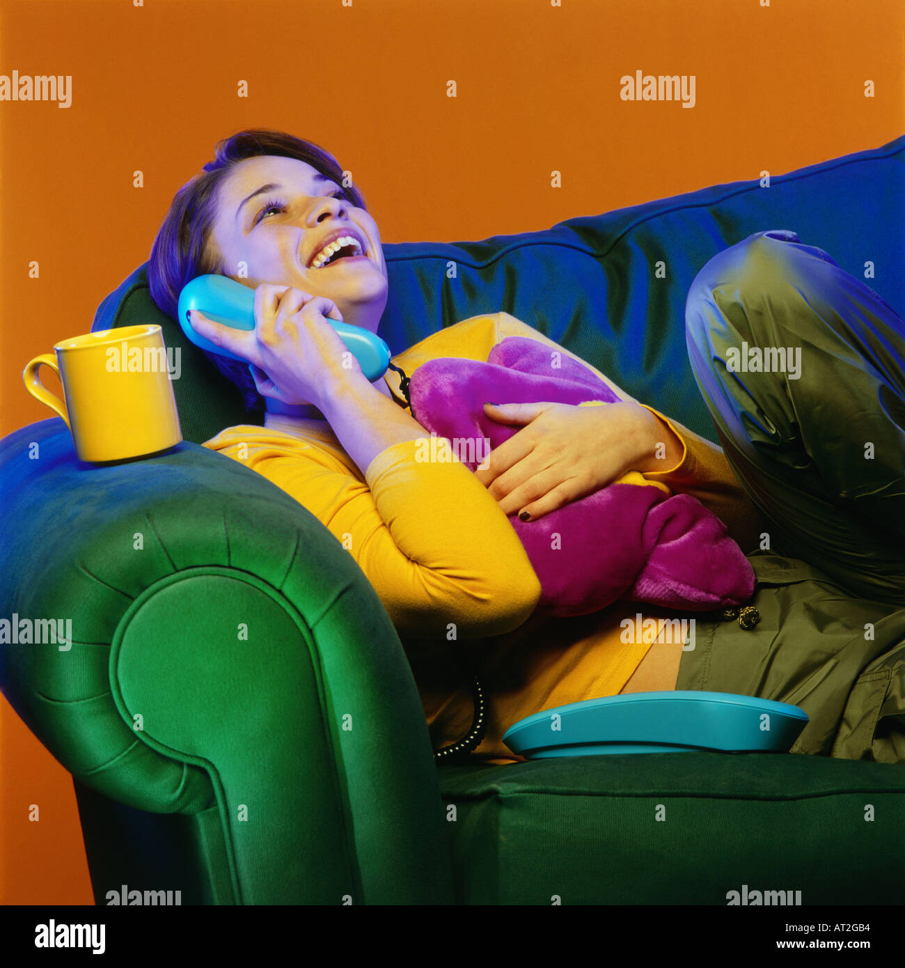 A woman relaxing on a sofa and speaking on the telephone Stock Photo