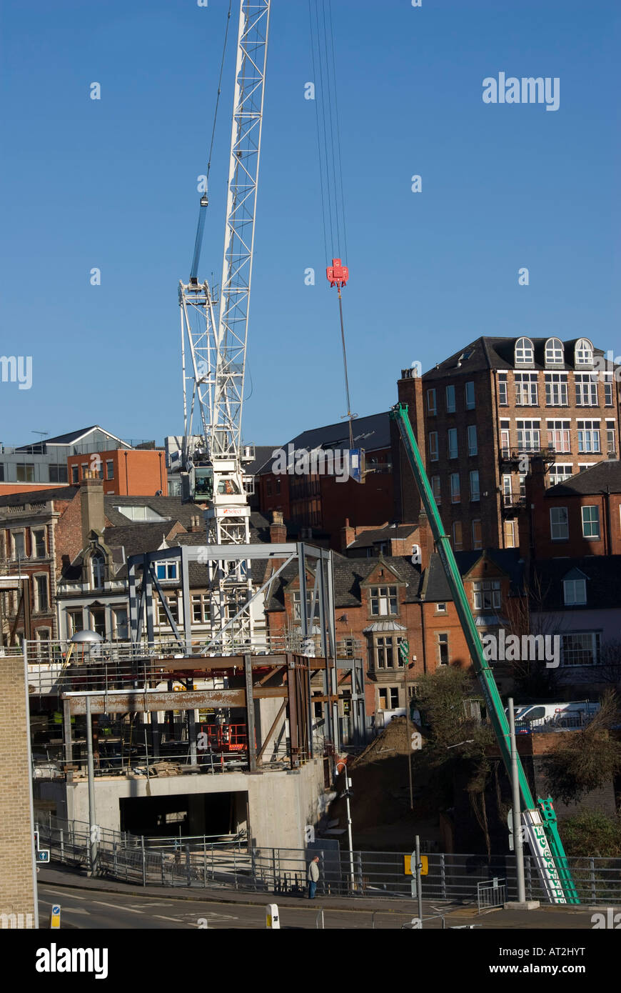 tower crane lifting skip over buildings Stock Photo