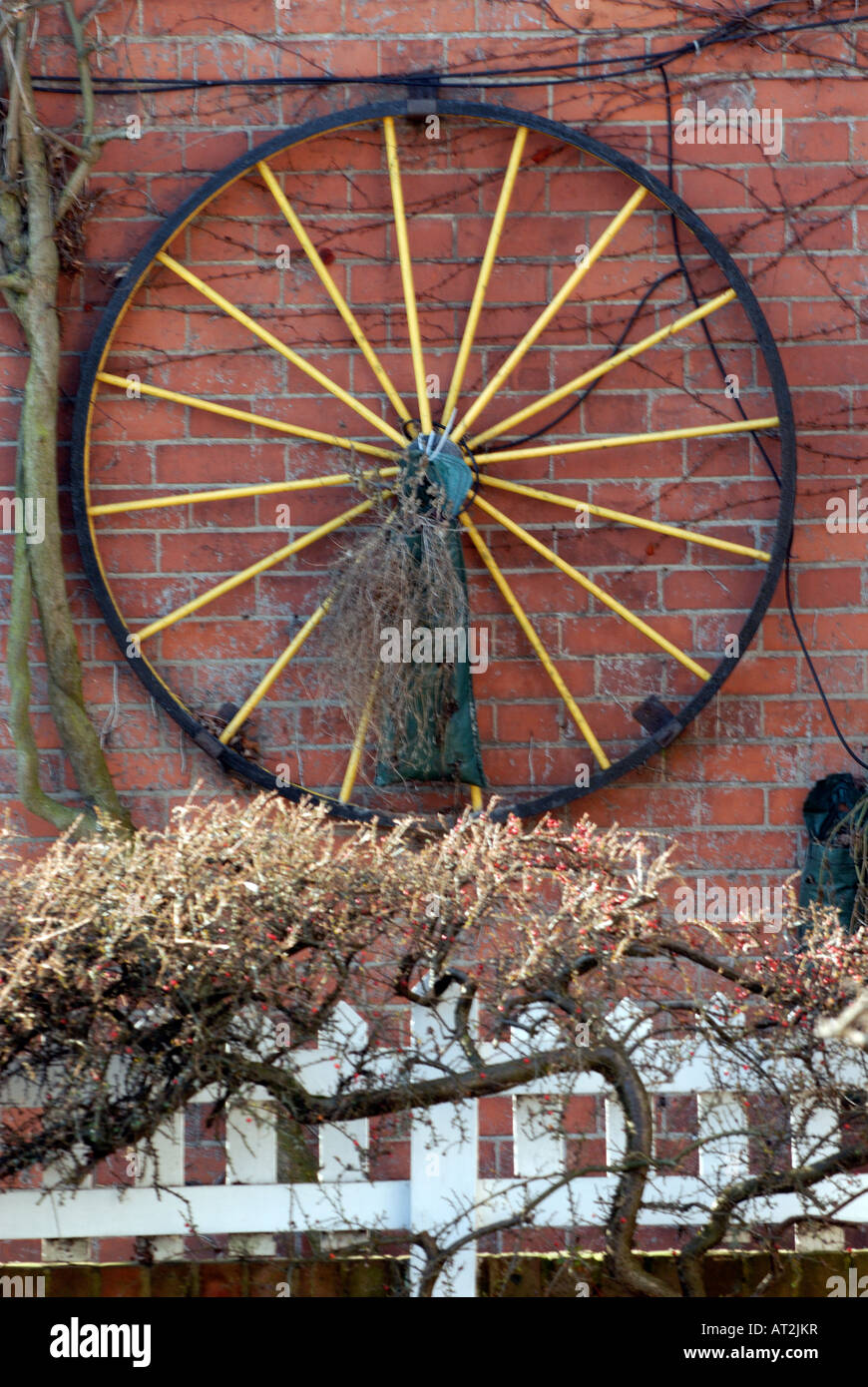 a cartwheel hanging hung on a wall for decoration outside of a typical old english country cottage in the gardens of a house Stock Photo
