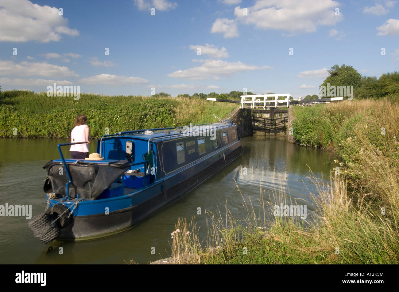 A woman steering the British narrowboat Fortuna at Caen hill locks on the Kennet & Avon canal, Devizes, Wiltshire, UK Stock Photo