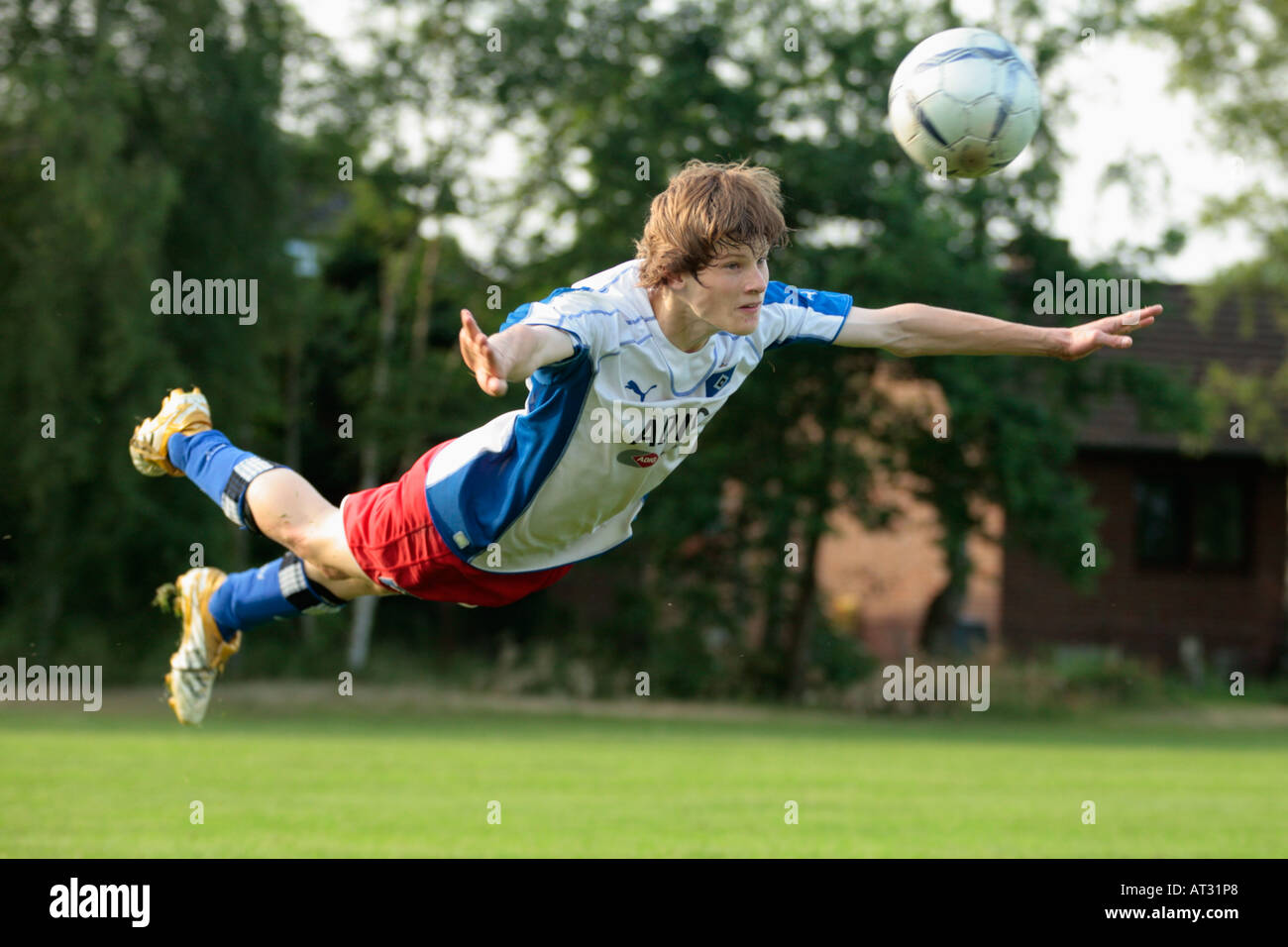 teenage boy at a football match jumping to head a ball Stock Photo Alamy