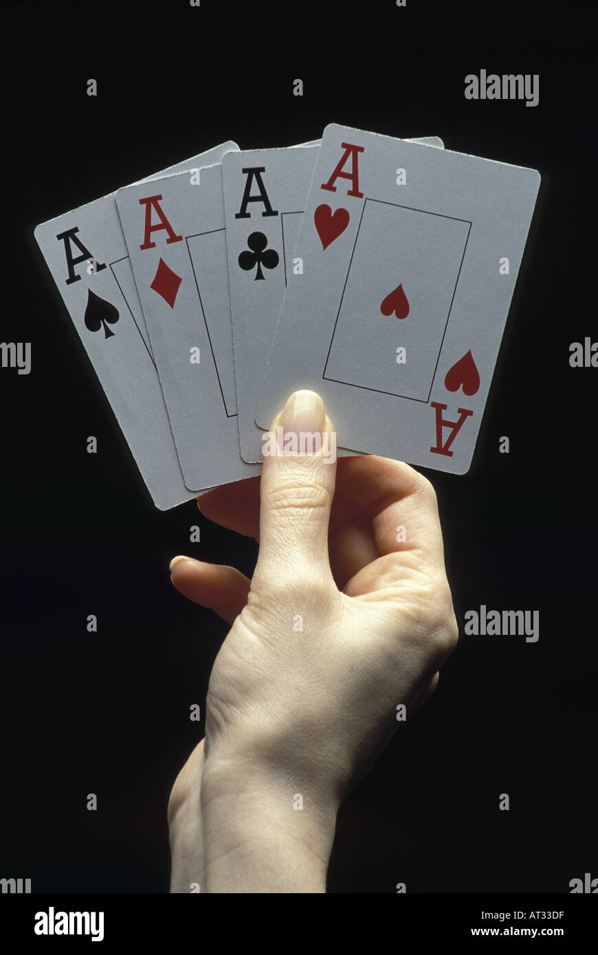 Hand holding four aces on black background Stock Photo