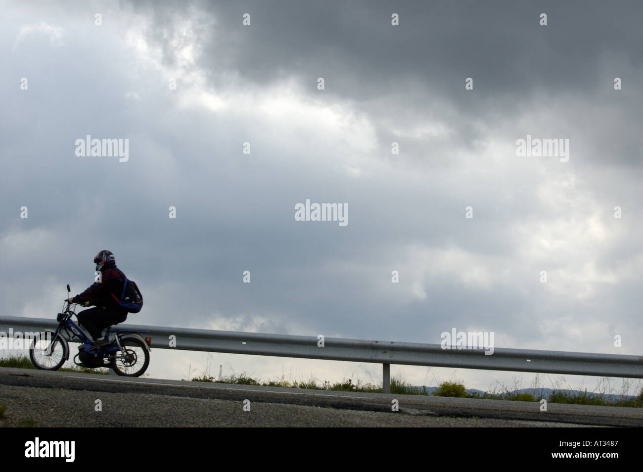 Moped on a road against a stormy sky, Saint-Paul-Trois-Châteaux, Drome, France. Stock Photo
