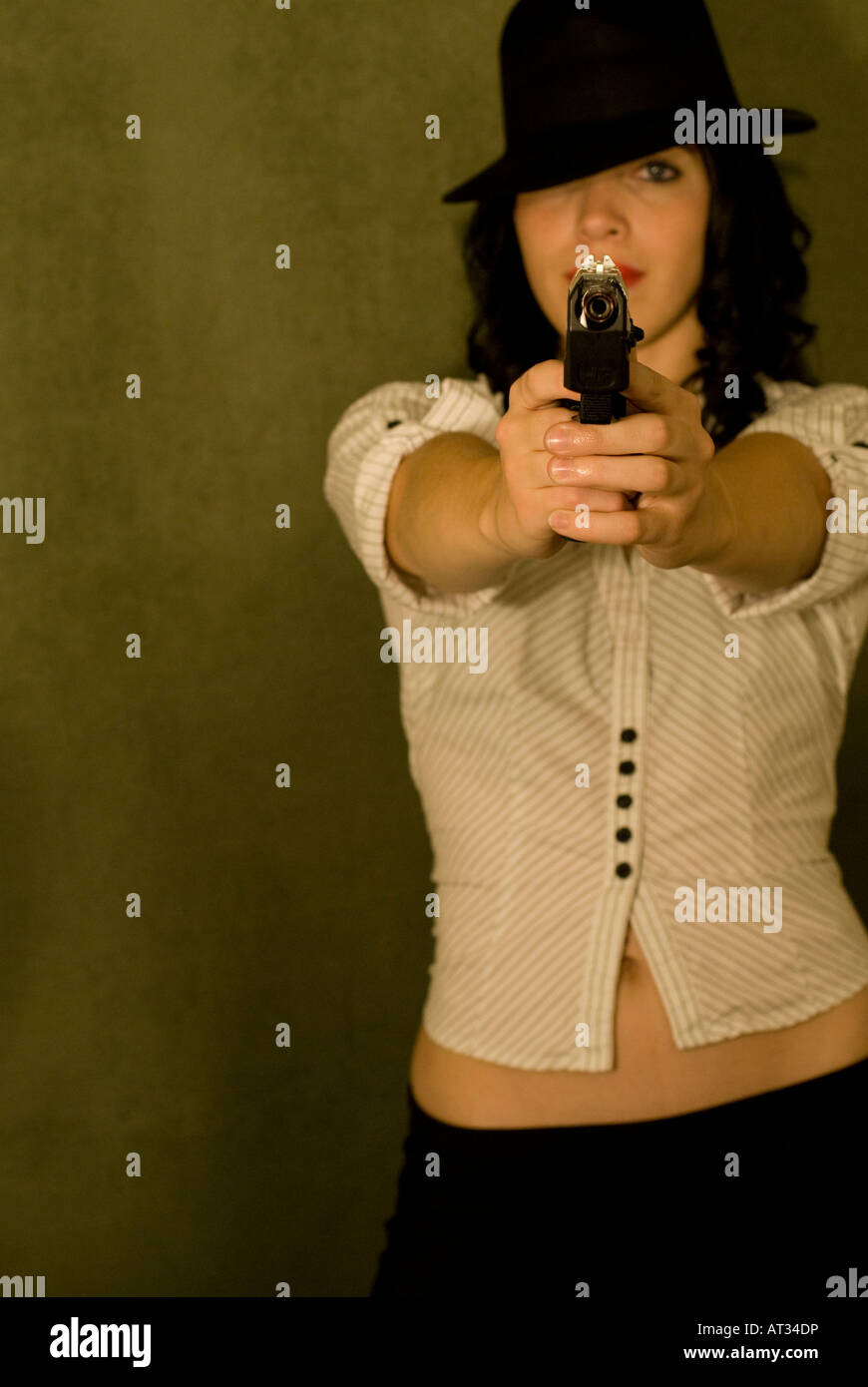Gorgeous female model posing with a gun in a studio Stock Photo - Alamy