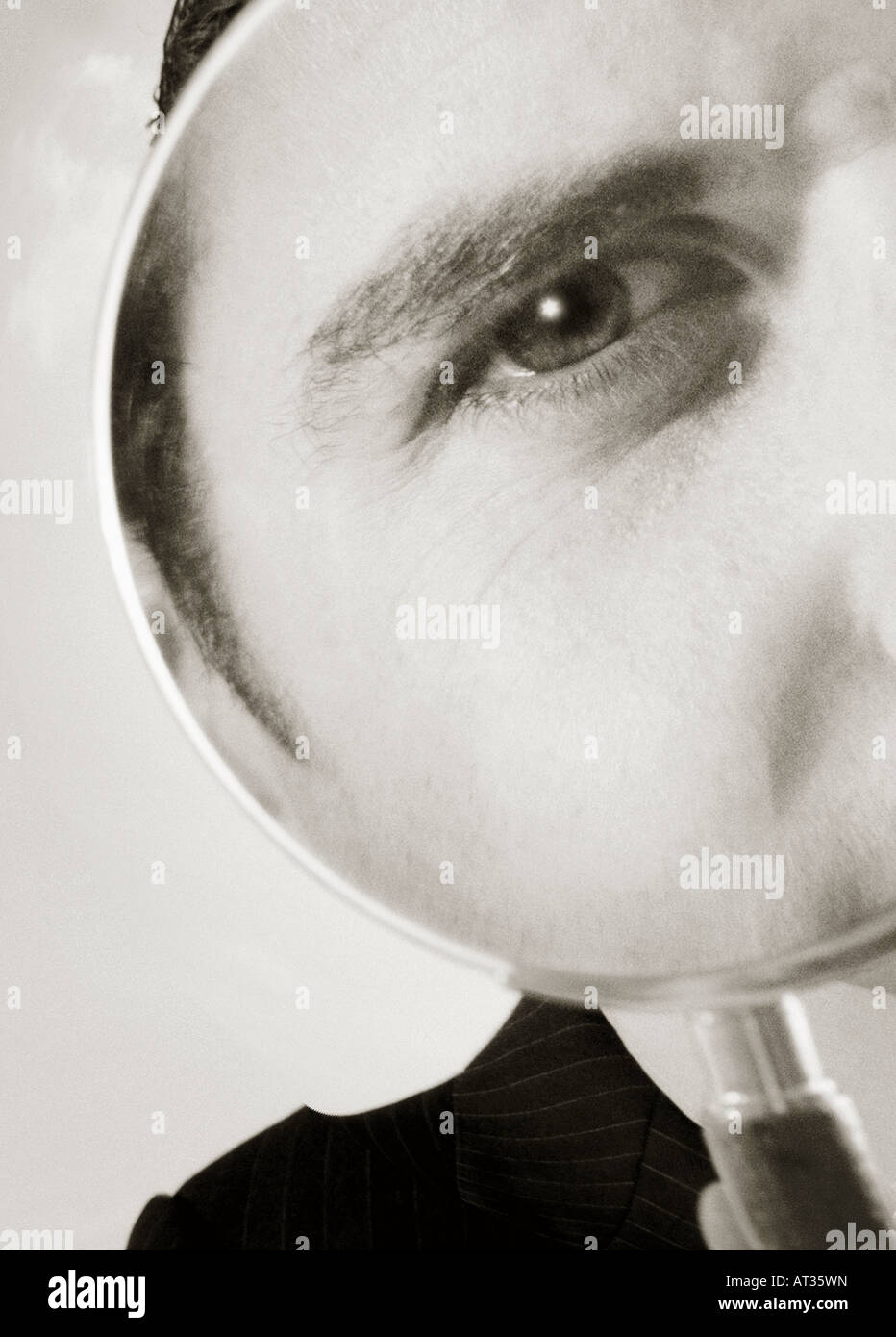 A man looking through a magnify glass Stock Photo - Alamy