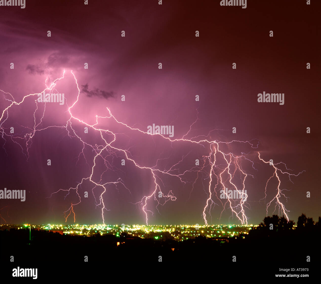 Many lightning bolts shoot across the night sky over a city Stock Photo