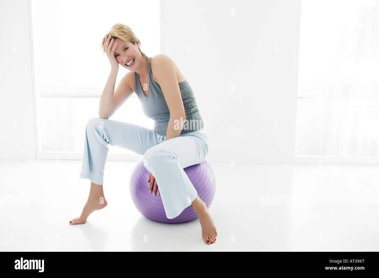 A woman sitting on an exercise ball, smiling Stock Photo - Alamy