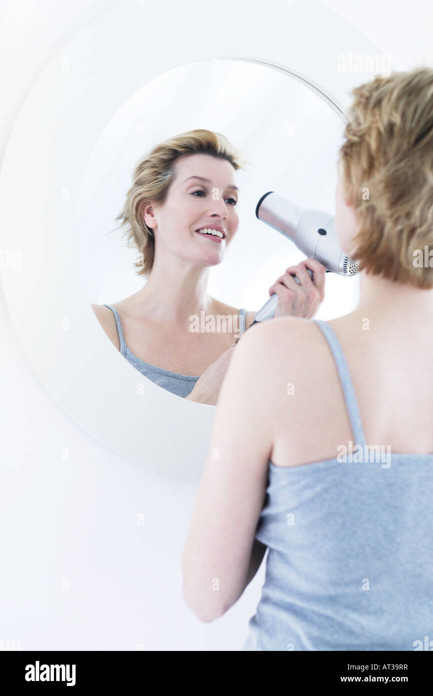 A woman drying her hair with a hairdryer Stock Photo - Alamy