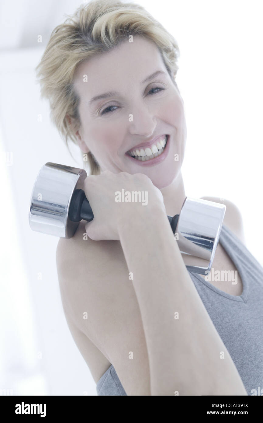 A woman holding a silver dumb bell Stock Photo