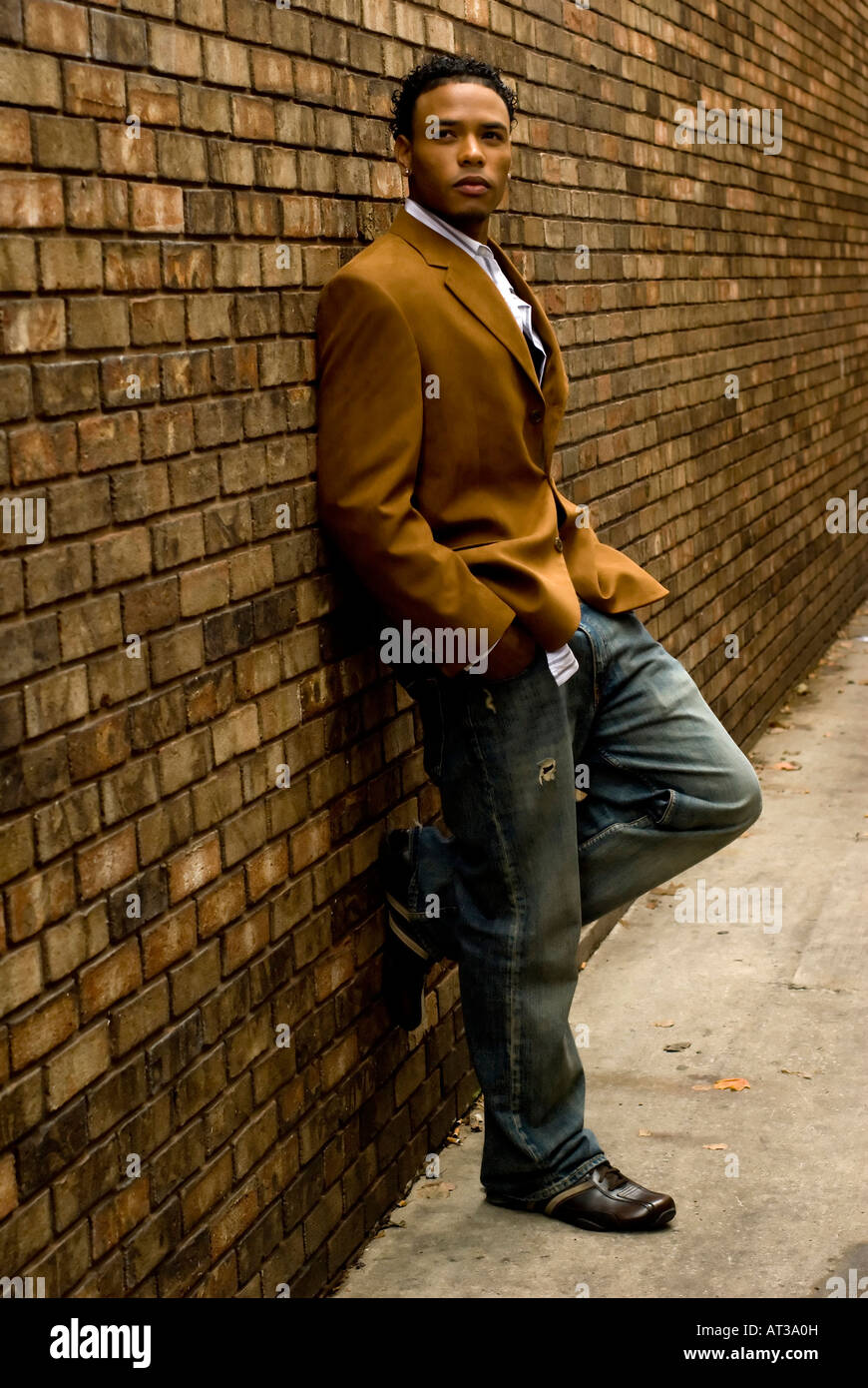 Attractive young man in a suit and jeans against a brick wall Stock ...