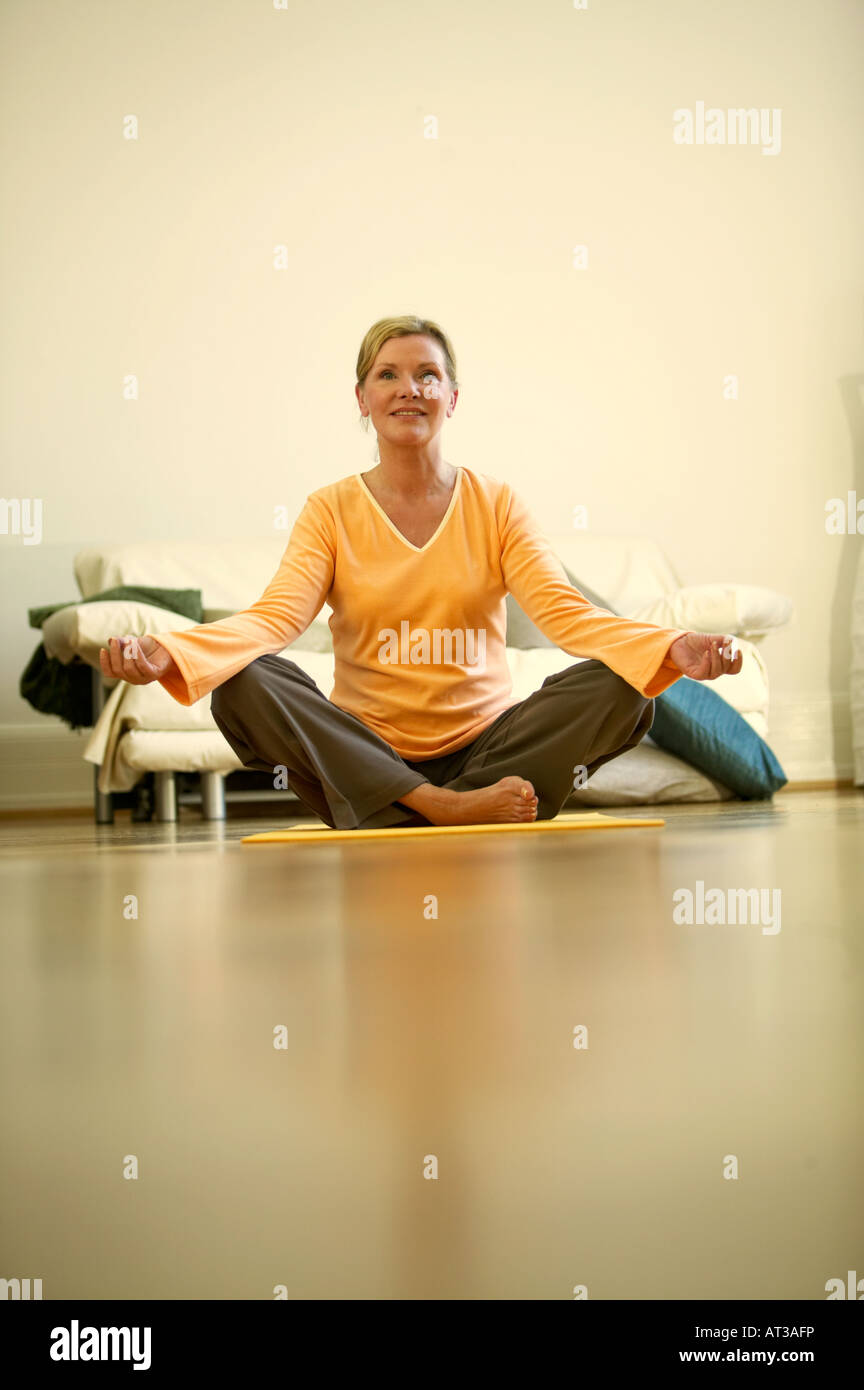 A woman sitting on a yoga mat smiling Stock Photo - Alamy