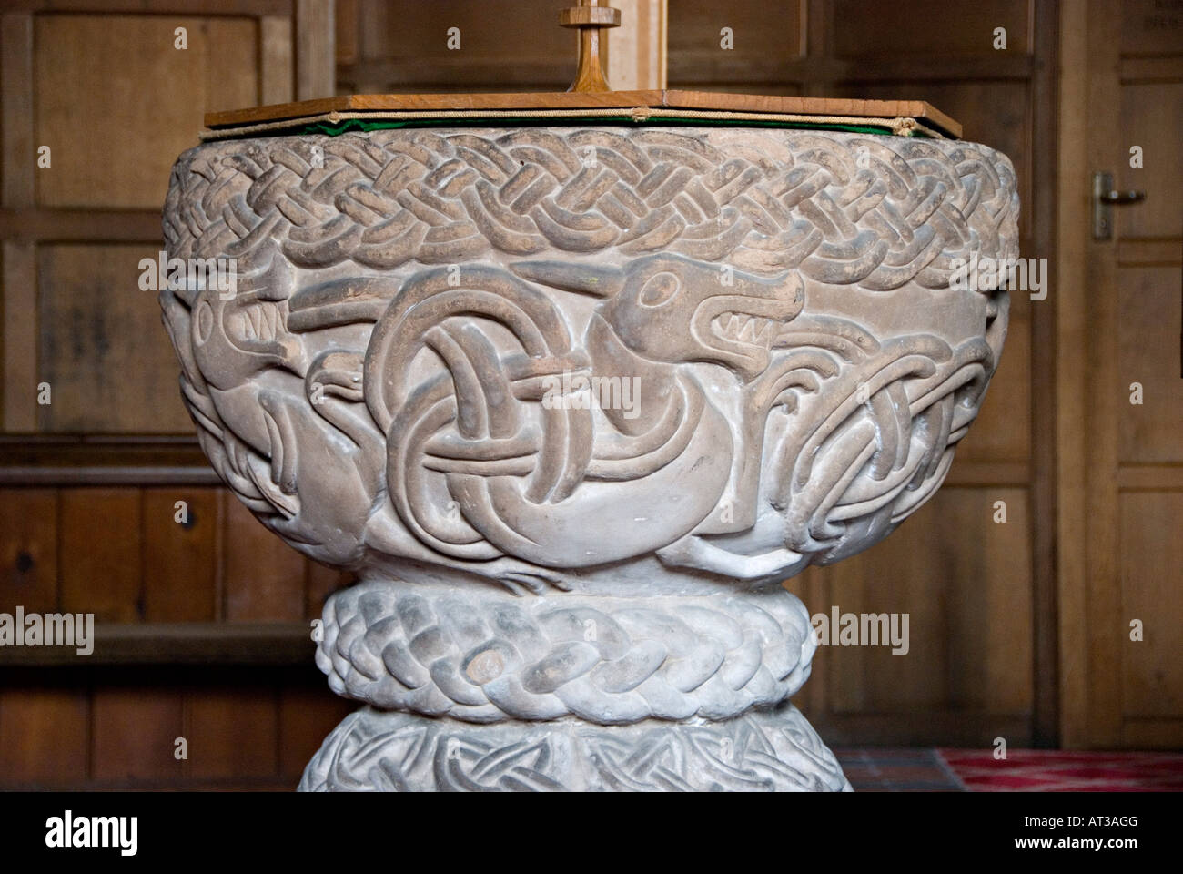 St Cassian's Church, Chaddesley Corbett, Worcestershire, UK. The ornate Romanesque 12c stone font, carved with a pattern of interlaced dragons Stock Photo