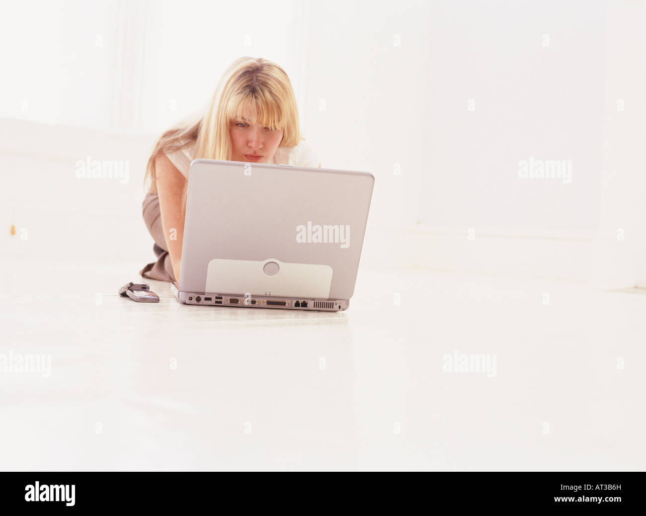 A woman sitting on the floor working on a laptop Stock Photo - Alamy