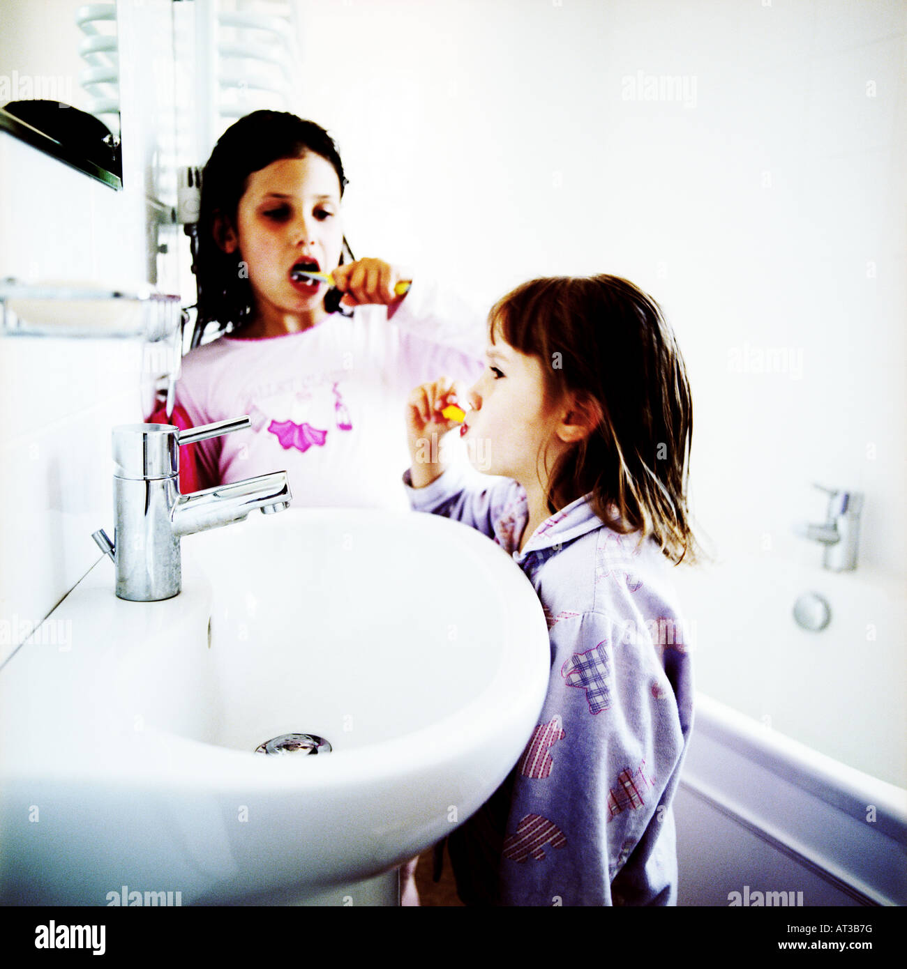 Two sisters in the bathroom cleaning their teeth Stock Photo