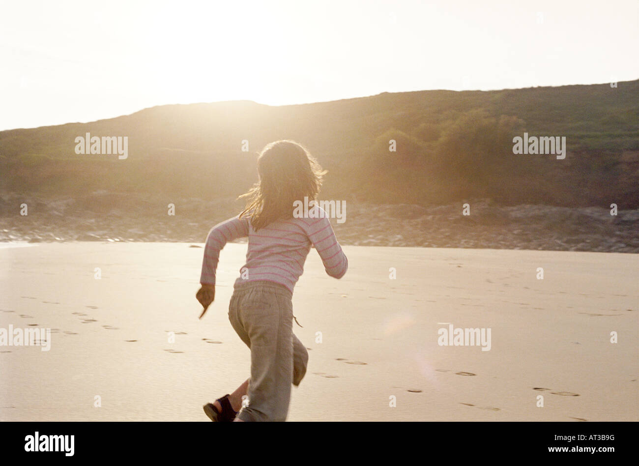 A young girl running along the beach Stock Photo