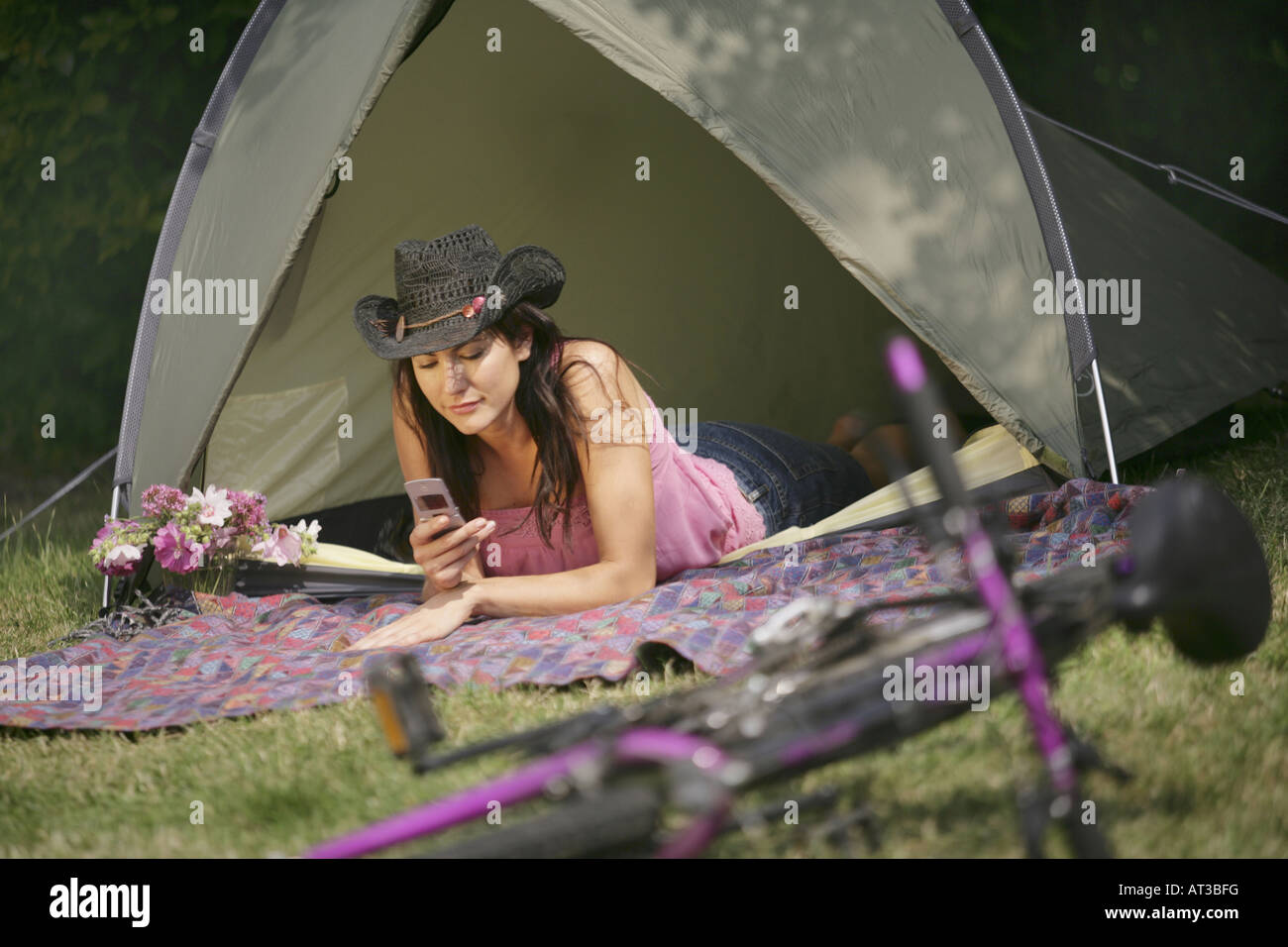 A dark haired girl in a tent texting on a mobile phone Stock Photo