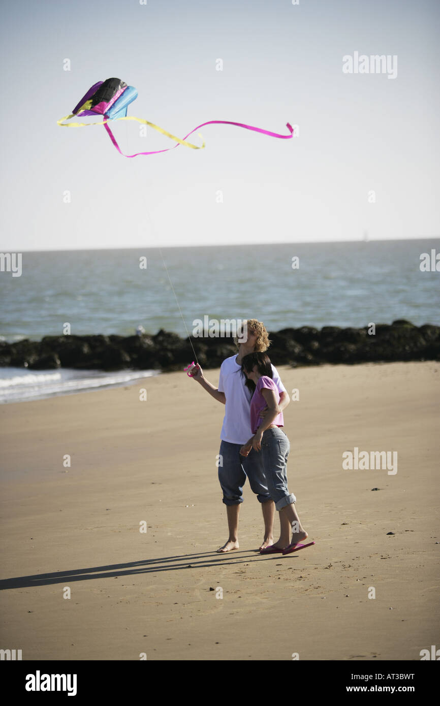 Couple on a beach flying a kite in late evening light Stock Photo - Alamy