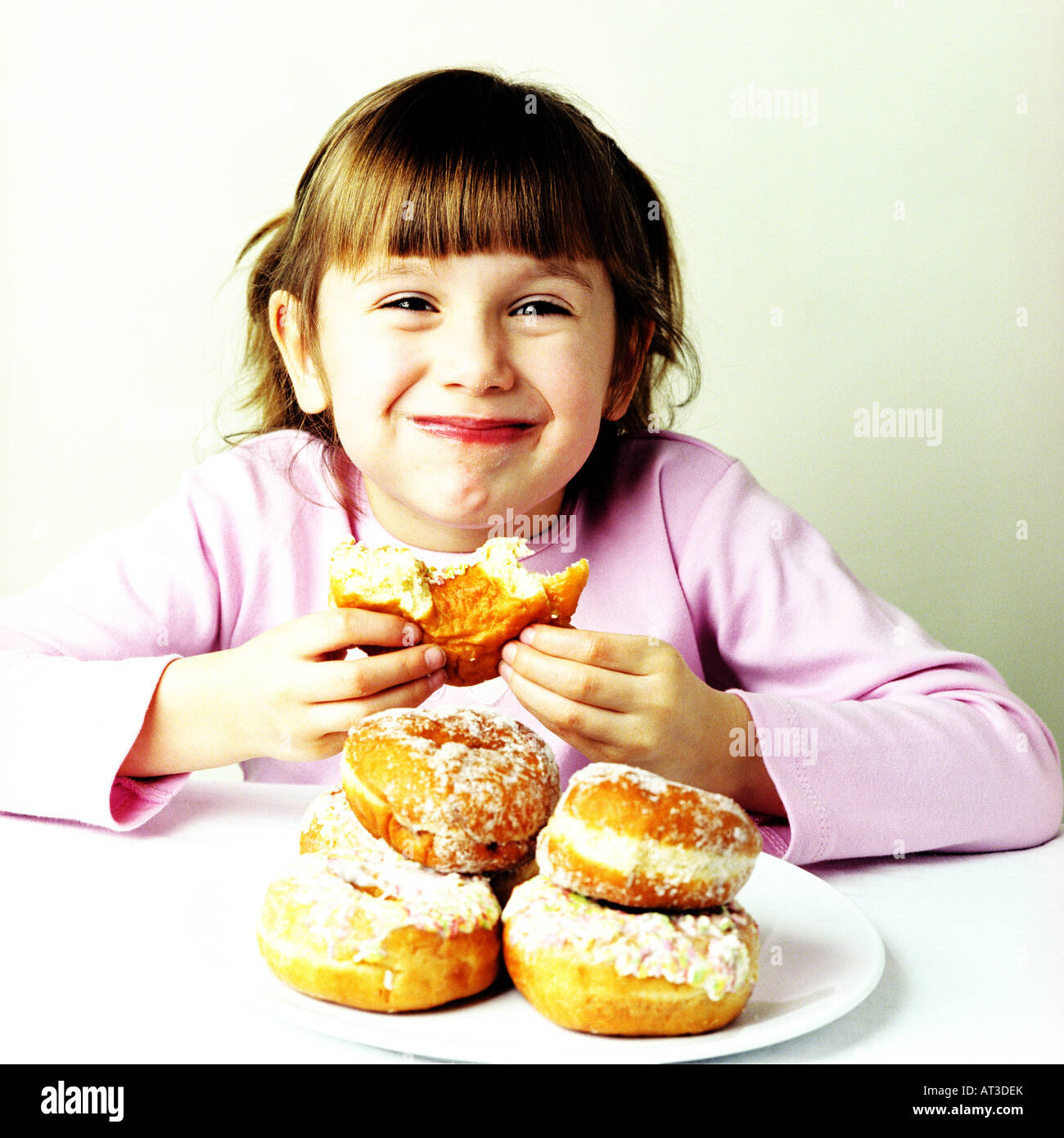 A small girl eating doughnuts Stock Photo