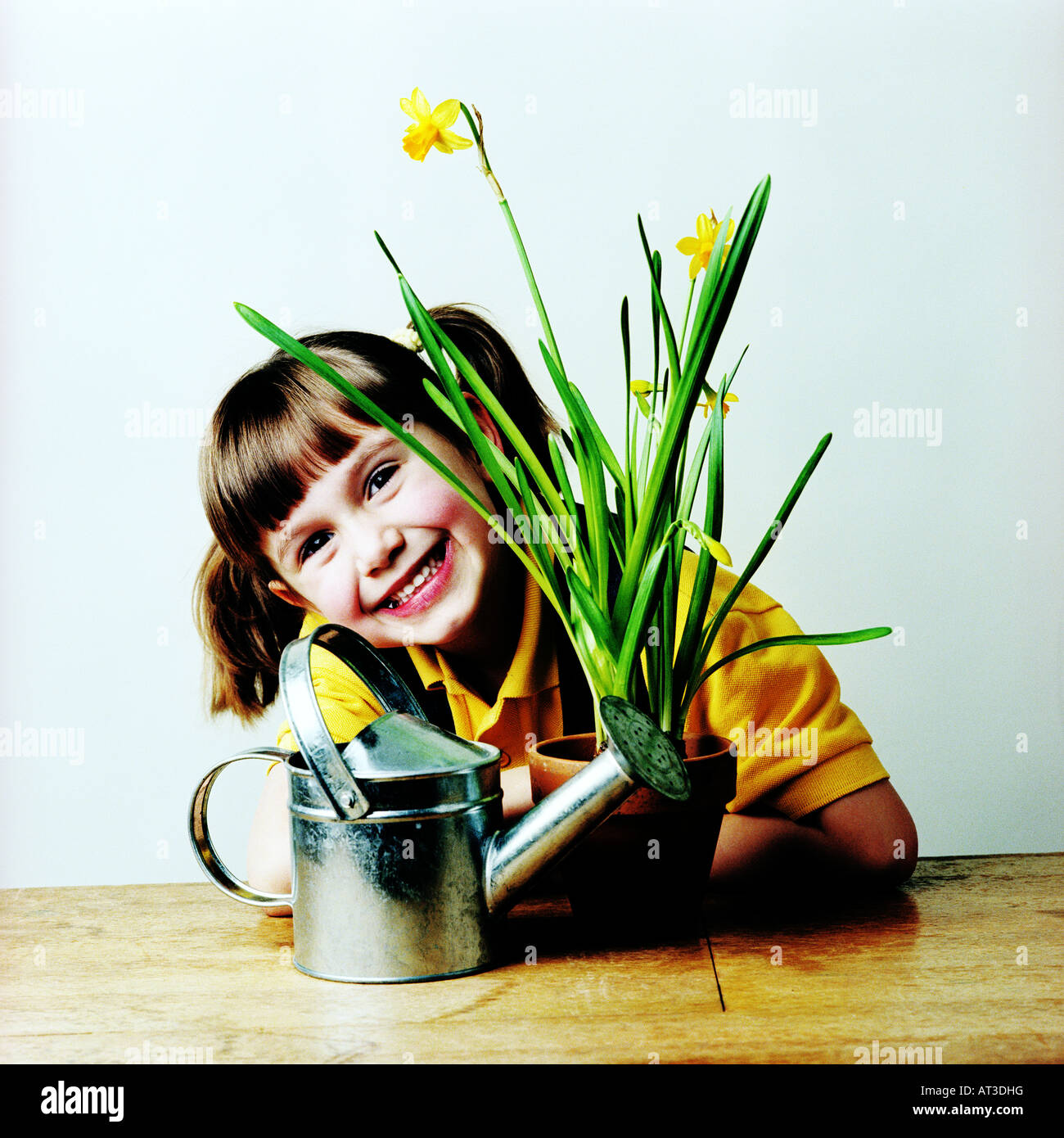 A girl with a watering can and pot plant, smiling Stock Photo