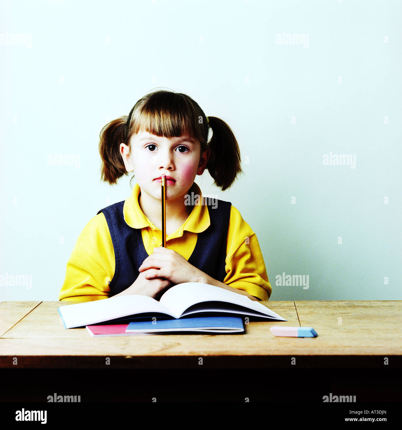 A school girl sitting at a desk thinking Stock Photo