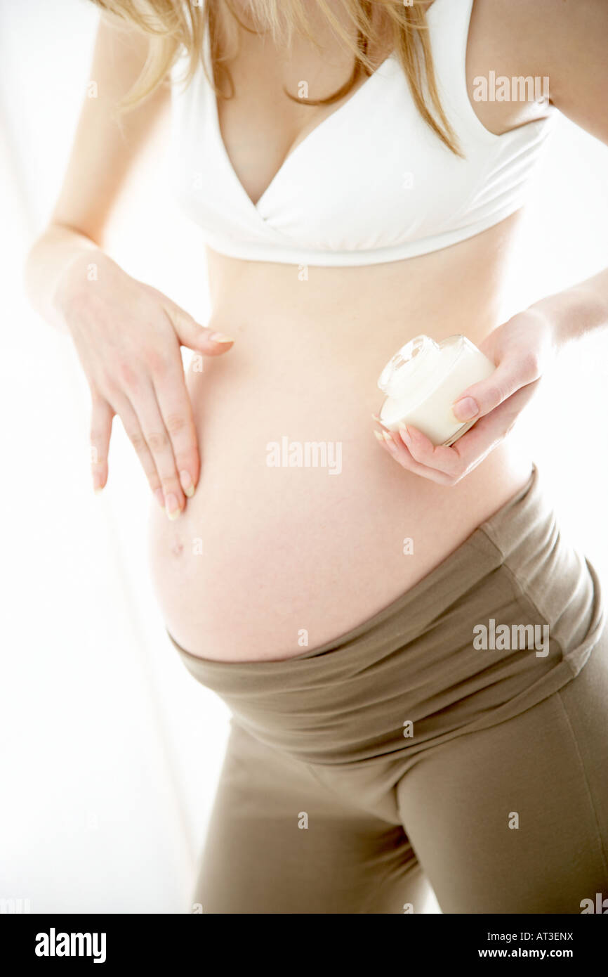 A pregnant woman applying moisturising cream to her tummy Stock Photo