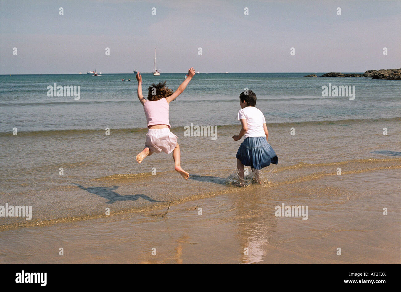 Two young girls jumping in the sea Stock Photo