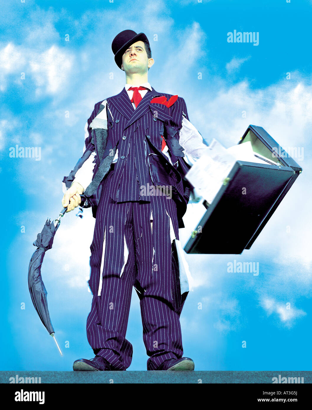 A businessman wearing a tattered suit, holding a briefcase and umbrella Stock Photo