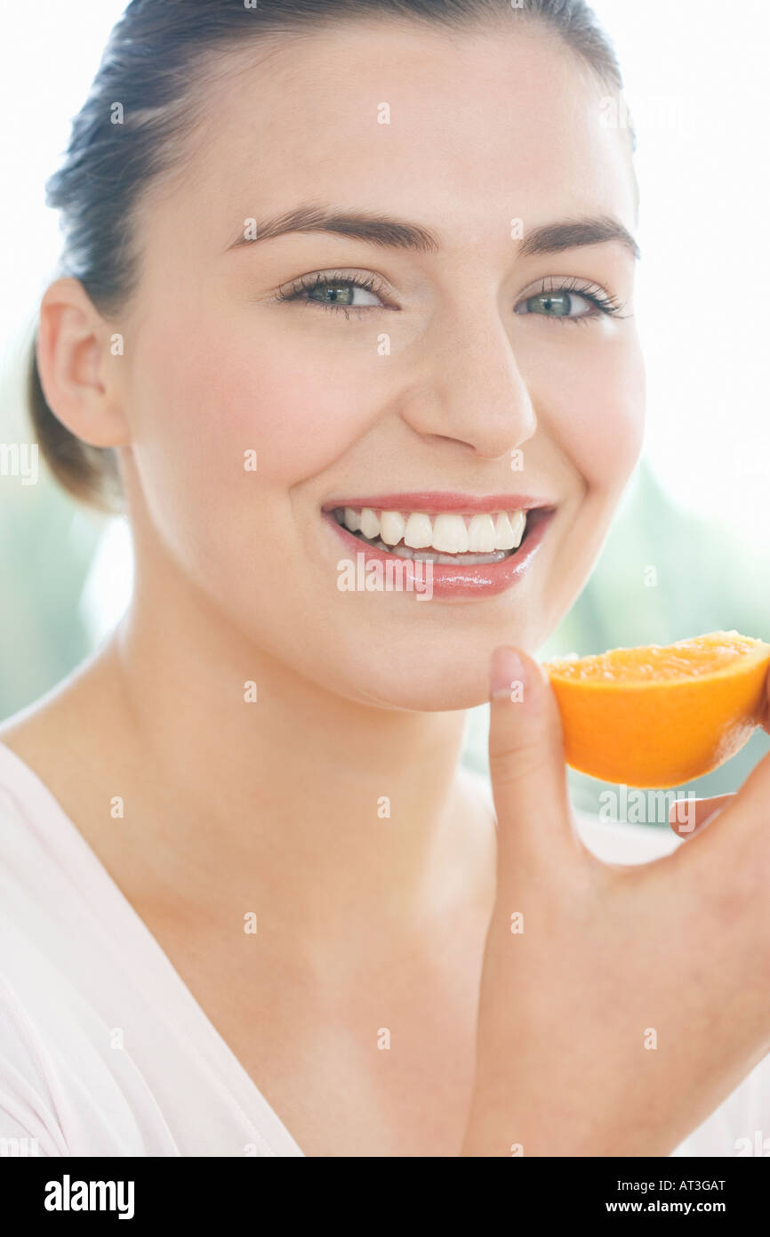 Young woman holding a piece of orange, smiling Stock Photo - Alamy