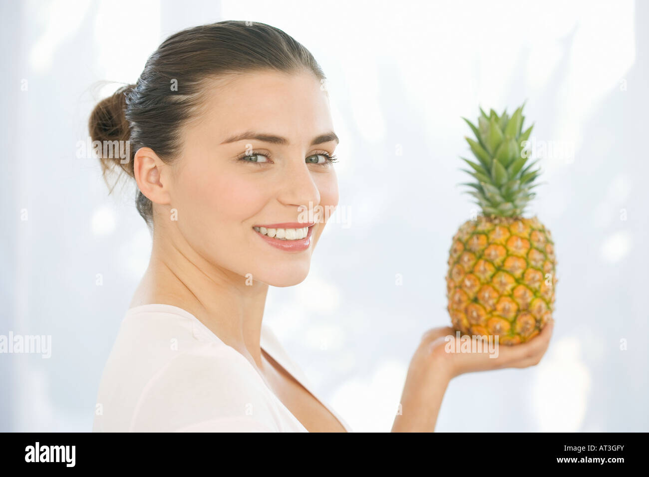 Young woman holding a pineapple, looking to camera Stock Photo Alamy