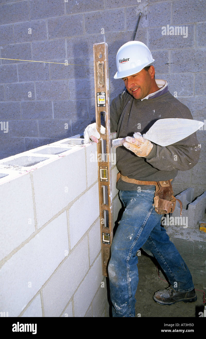 A mason uses a mason line and level to line up course with cinder block