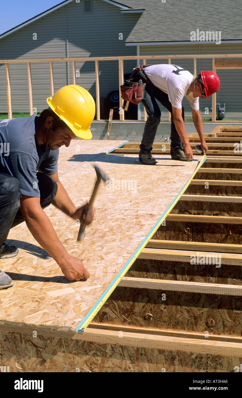 Construction workers installing the tongue and groove subfloor of a