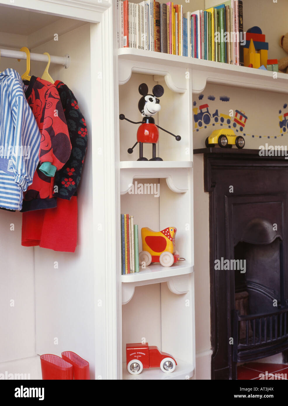 Childrens clothes hanging in cupboard beside toys on white storage shelves  beside fireplace Stock Photo - Alamy