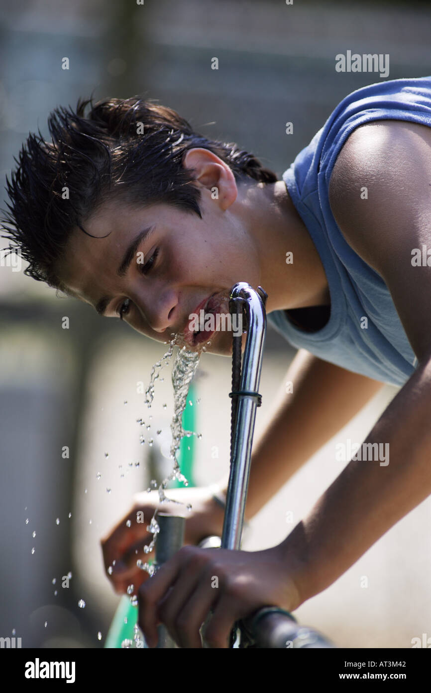 Teenage boy drinking water from fountain Stock Photo