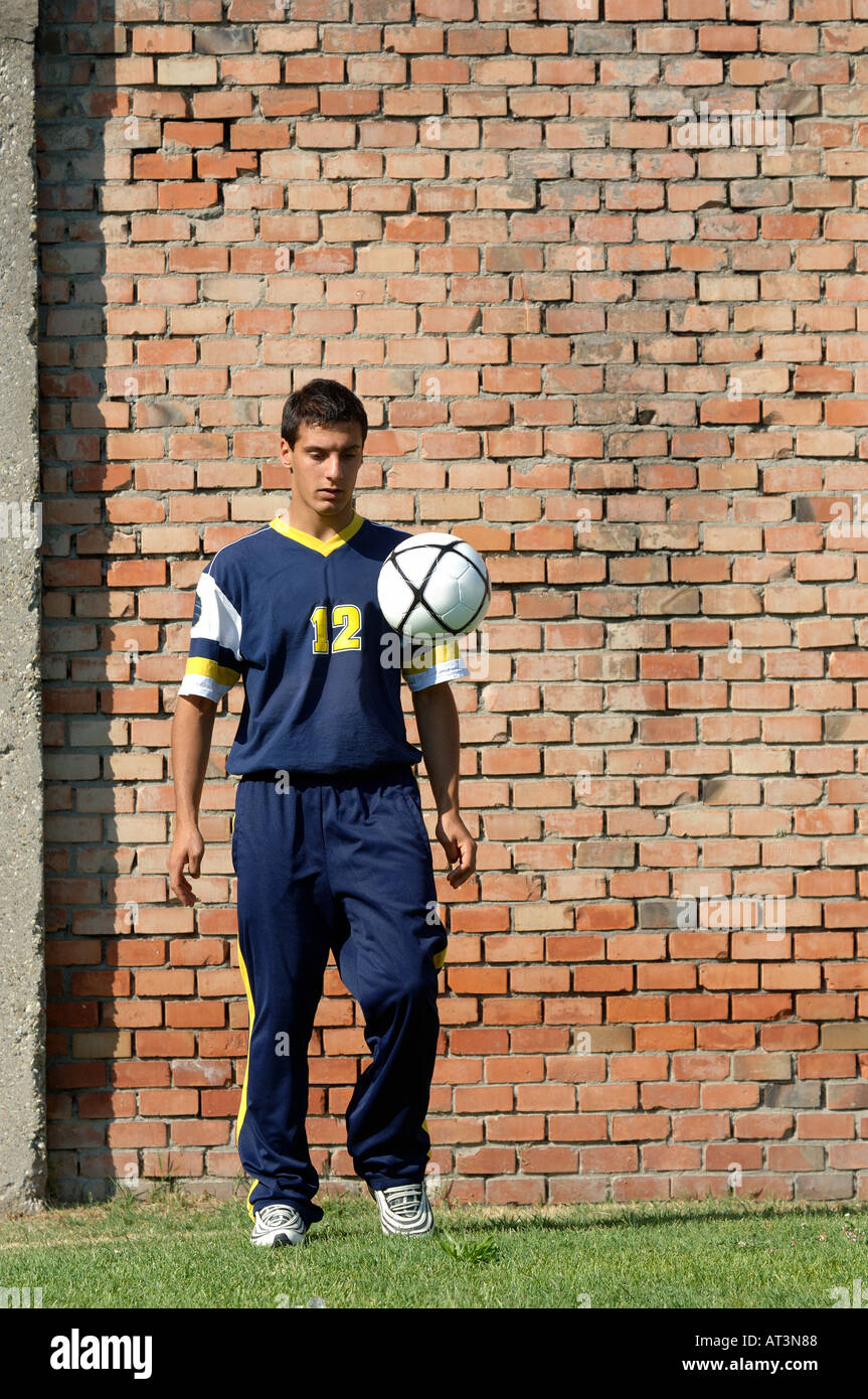 Young man juggling soccer ball in front of brick wall Stock Photo Alamy