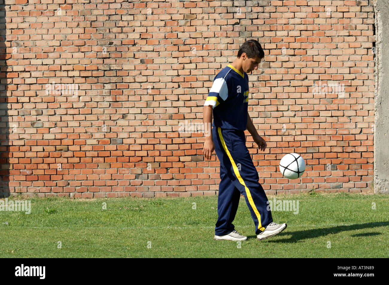 Young man juggling soccer ball in front of brick wall Stock Photo Alamy
