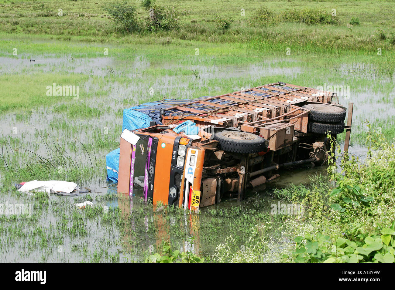 a truck lies in a paddy field after an accident on the road in India Stock Photo