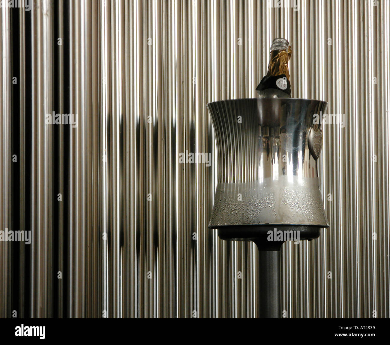 an empty champagne bottle in a frosted silver ice bucket in front of chrome pipes silver tubes Stock Photo