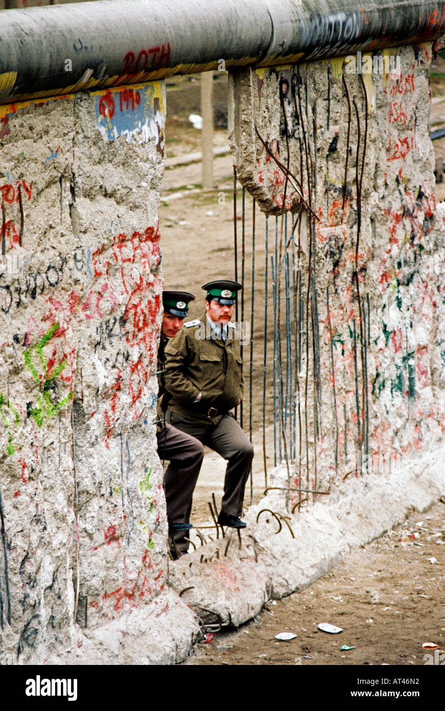 The Fall of the Berlin wall, 1989. East German guards watch the West pass by through a hole in the wall. Stock Photo