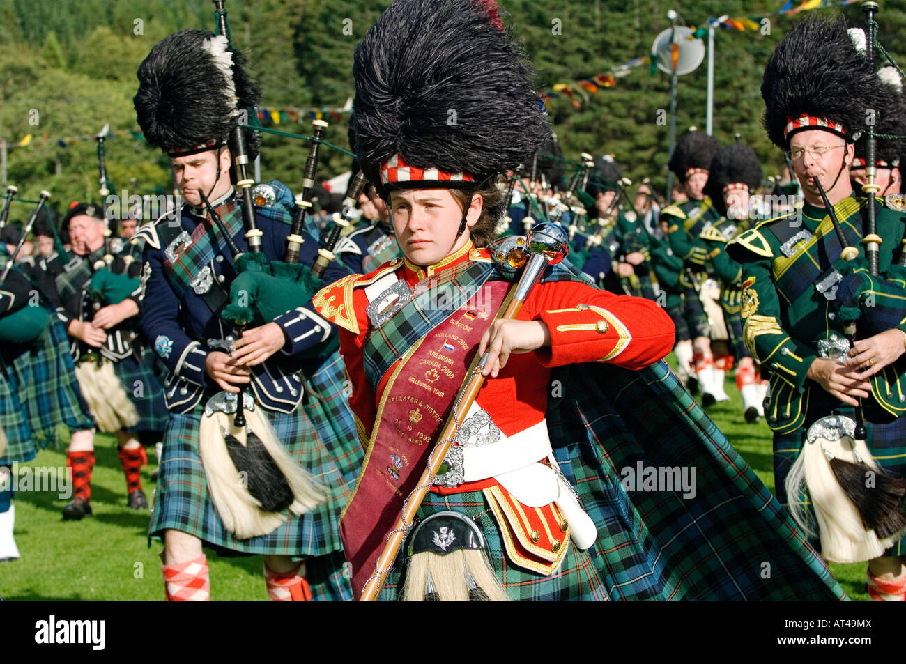 Scottish traditional pipe band majorette leads bagpipe band at the Lonach Highland Games at Strathdon, near Balmoral, Scotland Stock Photo
