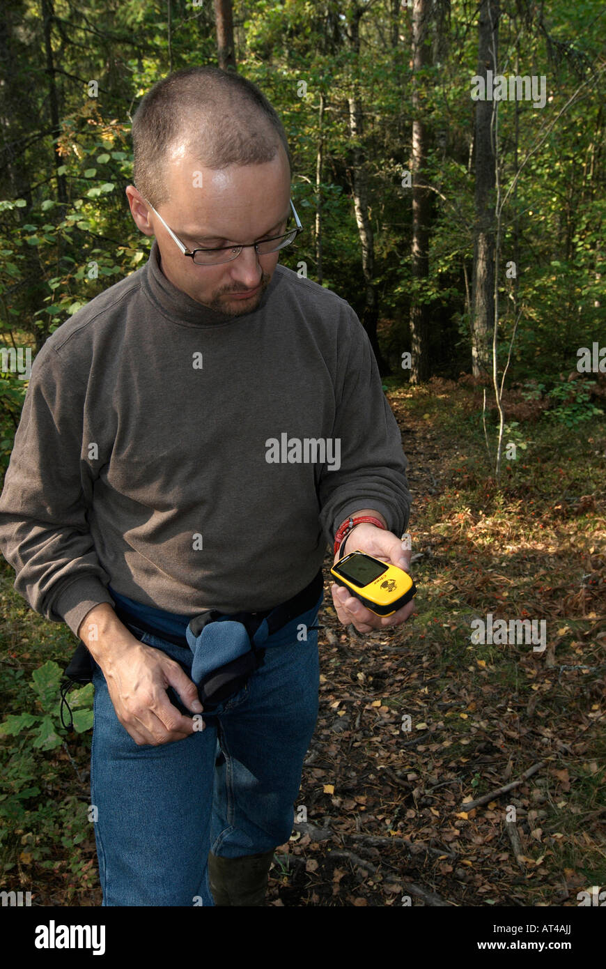 Male hiker verifying the course with a GPS receiver in the forest of Hagelstena Uppsala Lan Sweden September 2007 Stock Photo