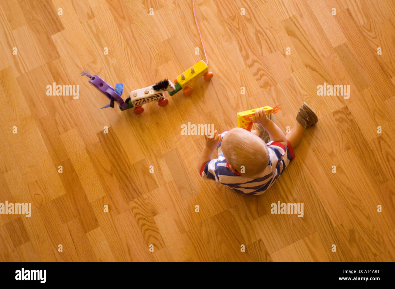 Toddler Playing With Wooden Toys On The Floor Stock Photo