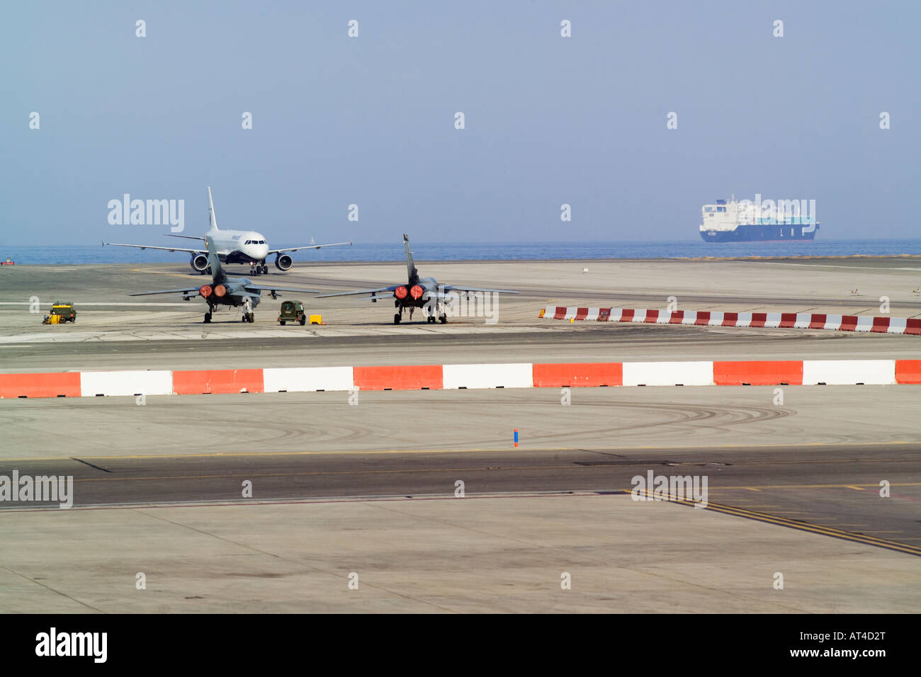 Monarch A320 Airbus Airliner landing at Gibraltar Airport with Tornado fighter planes in the foreground Stock Photo
