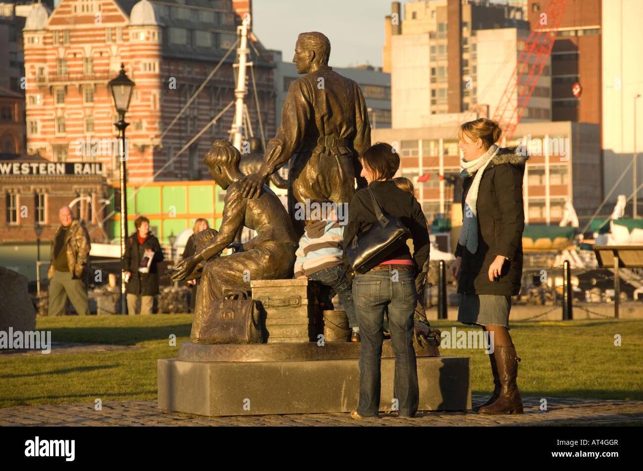 People looking at statue Liverpool docks waterside riverfront at dusk
