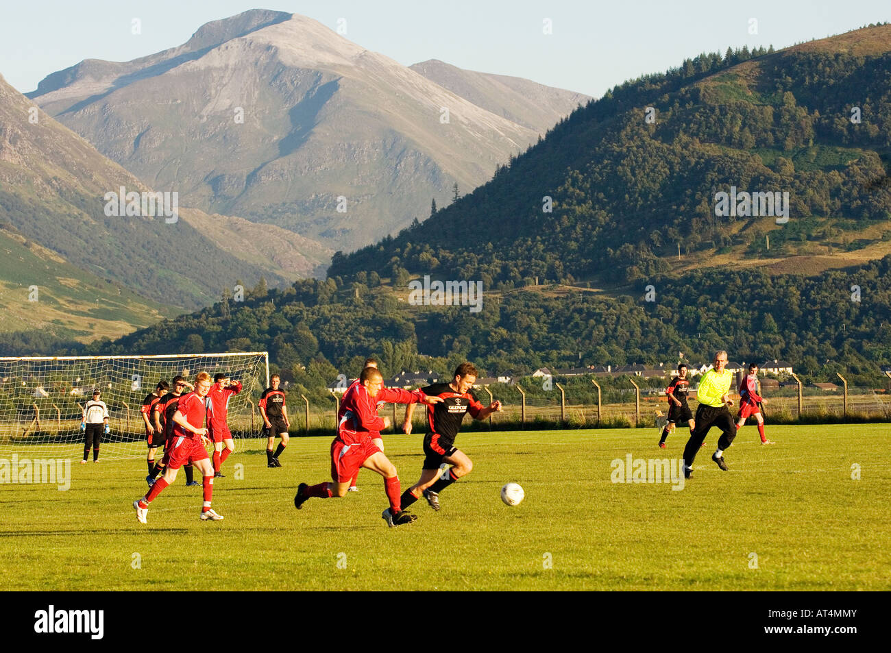 Local football teams Ballachulish and Buckfast play on pitch at Fort William below entrance to Glen Nevis. Highland, Scotland Stock Photo