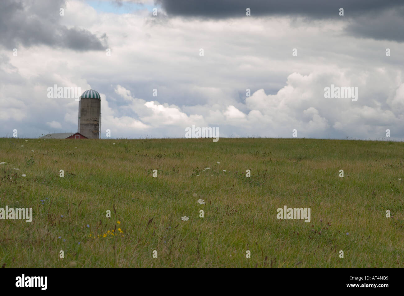 Barn silo on top of hill with stormy sky in background Stock Photo