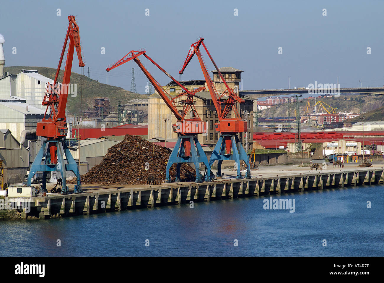 cranes loading and discharging scrap heaps in the port of the bilbao mouth of a river Stock Photo