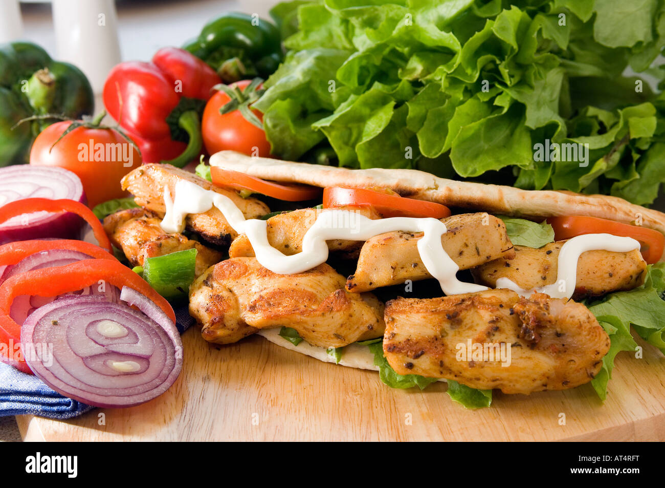 A fresh hot Chicken shish kebab served on a wooden platter in a pita bread with salad & mayonaise Stock Photo