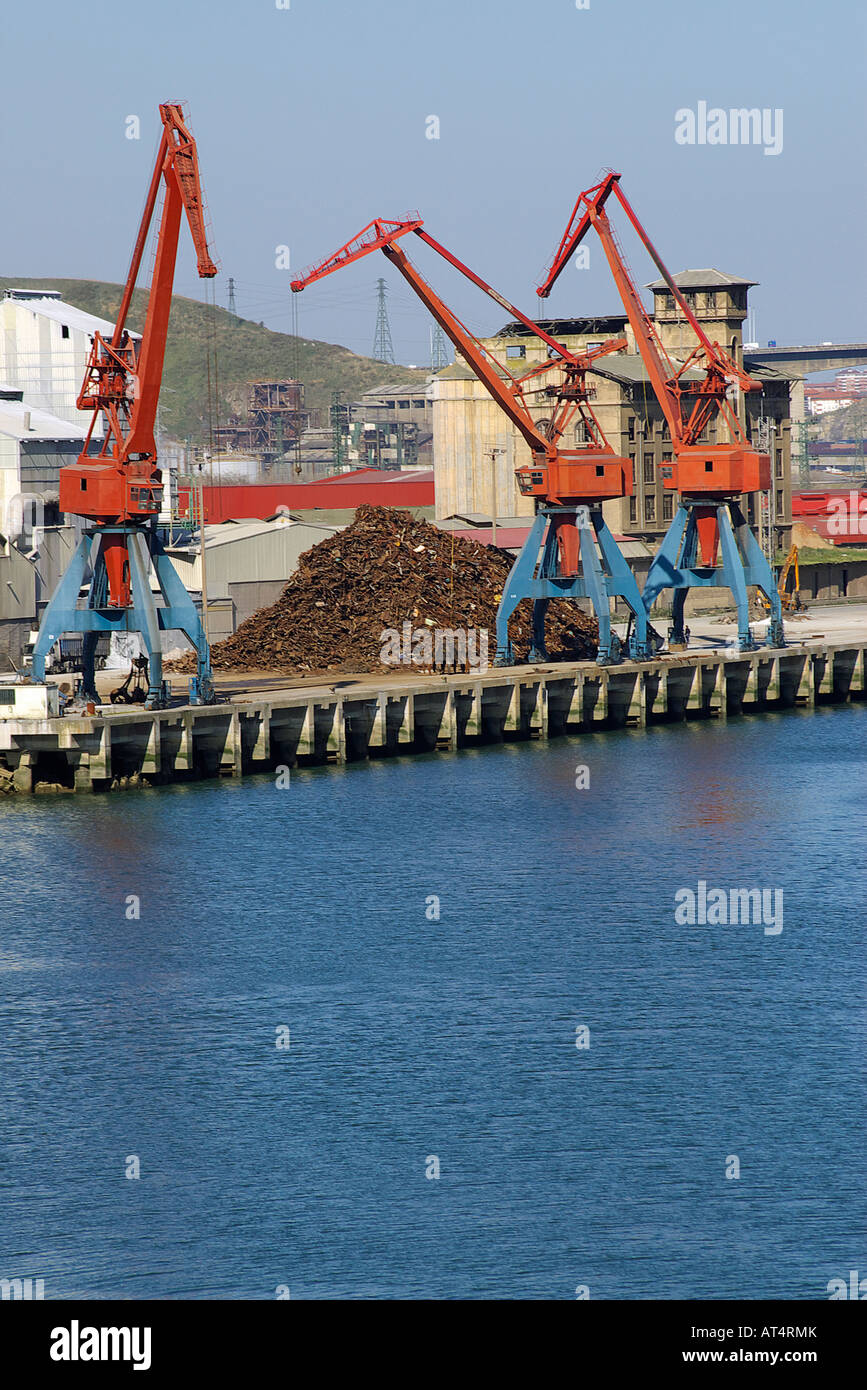 cranes loading and discharging scrap heaps in the port of the bilbao mouth of a river Stock Photo