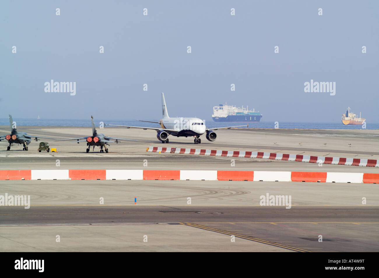 Monarch A320 Airbus Airliner landing at Gibraltar Airport with Tornado fighter planes in the foreground Stock Photo
